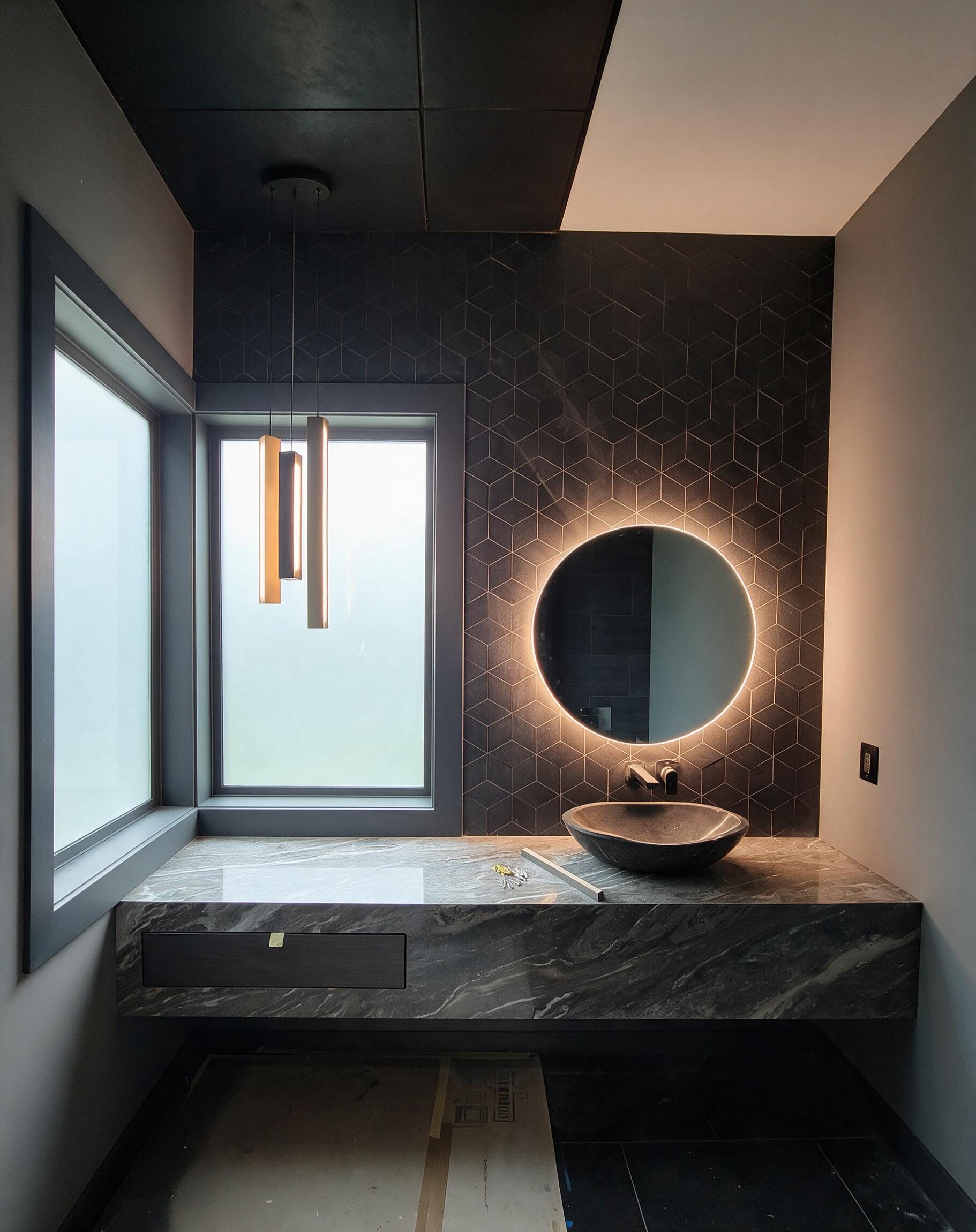 Dark stone bathroom vanity with round backlit mirror